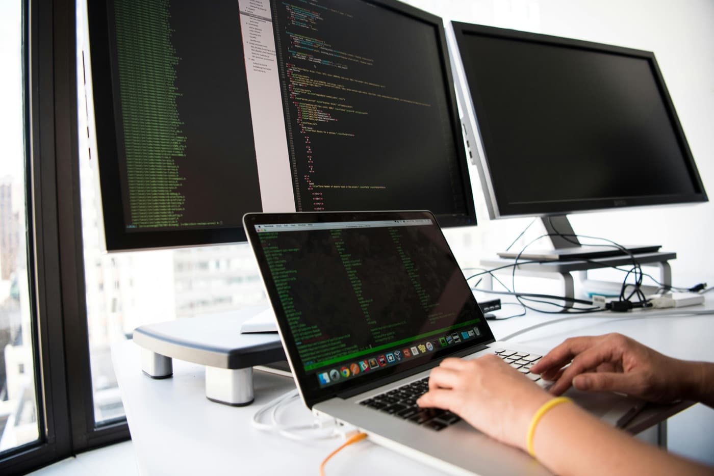 Engineer reviewing code on multiple screens
